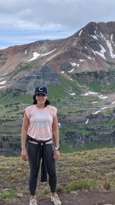 Colorado Springs Massage Therapist by popular Colorado massage blog, Camino Massage: image of a woman wearing workout clothes and standing outside with some mountains in the background. 